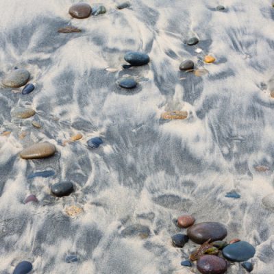 Pebble on sandy beach and stones